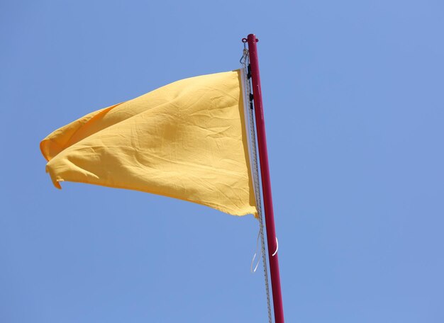 Große gelbe Flagge schwingt im blauen Himmel als Warnung