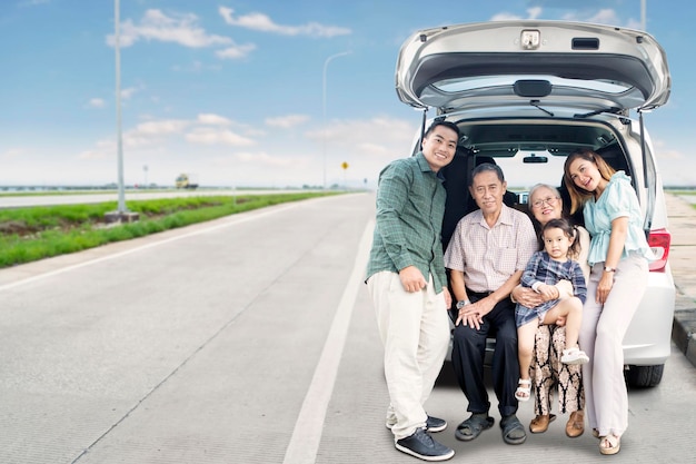Große, glückliche Familie sitzt auf dem Kofferraum