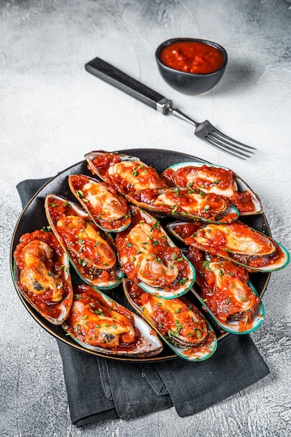 Große grüne Muscheln gekocht in Tomatensauce mit Knoblauch, Petersilie und Zitrone Weißer Hintergrund Ansicht von oben