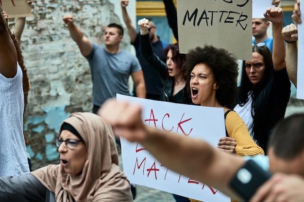 Große Gruppe unzufriedener Menschen, die den Protest gegen Black Lives Matter anschreien. Der Fokus liegt auf einer jungen schwarzen Frau, die ein Banner trägt