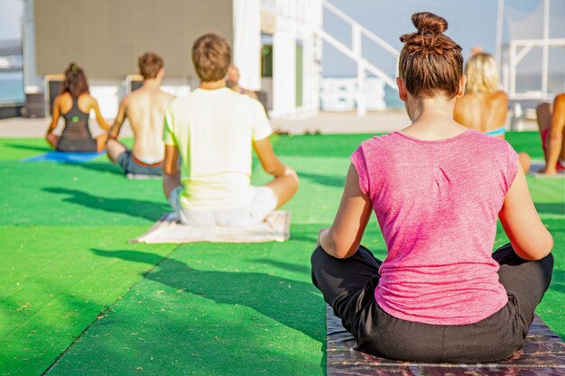 Große Gruppe von Erwachsenen, die einen Yoga-Kurs draußen im Park besuchen