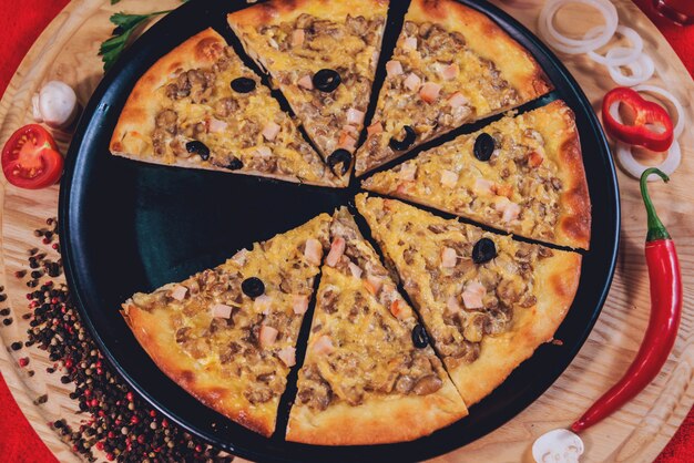 Große heiße Pizza auf dem schwarzen Teller.