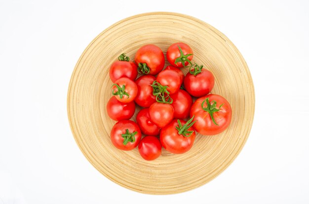 Große hölzerne Bambusschale mit reifen Tomaten. Studiofoto.