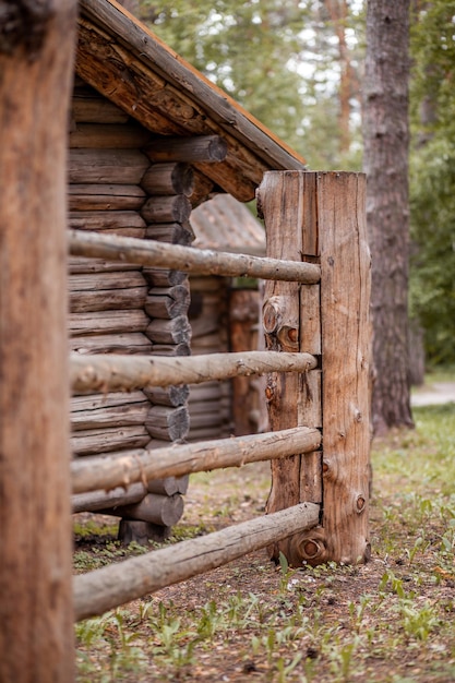 Große Holzzaunpfähle, die ein altes Holzhaus im Wald umschließen Wie Menschen Häuser bauten