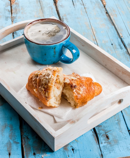 Große Kaffeetasse, Croissant und Zeitung