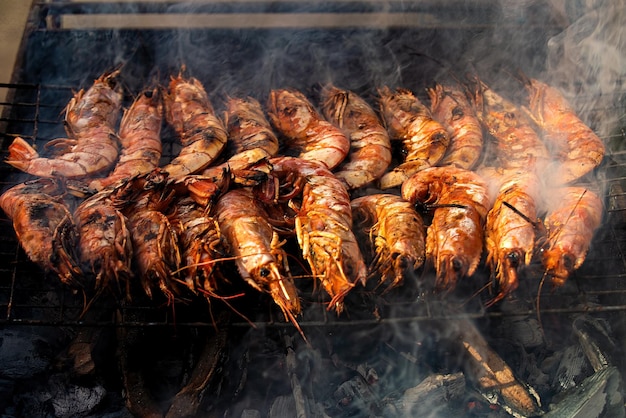 Große Kaisergranaten mit Schale liegen mit Rauch auf dem Grill