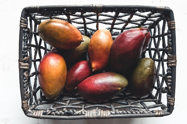 Große Mangos in einem Weidenkorb auf Weiß