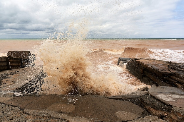 Große Meereswelle mit Spritzern stürzt auf einem Wellenbrecher aus Stein ab