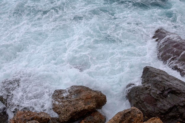 Foto große meereswellen schlagen gegen die felsen und bilden weißen schaum