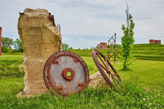 Foto große metallgetriebe und zahnräder rosten und rosten gegen zerstörte betonpfeiler auf einem grasbewachsenen feld