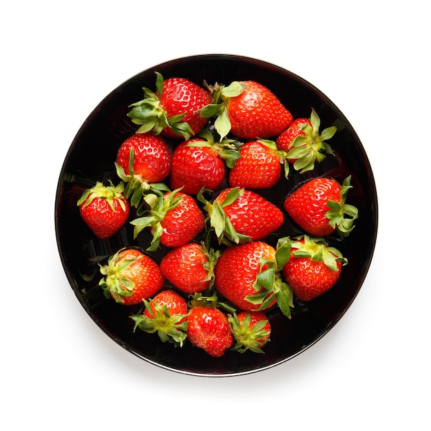 Große reife saftige Beeren von Bio-Erdbeeren in einem schwarzen runden Teller, isolierte Draufsicht
