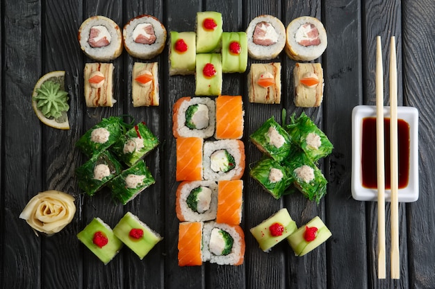 Große Reihe von Brötchen, Sojasauce und Stäbchen (Hashi) auf dunkel