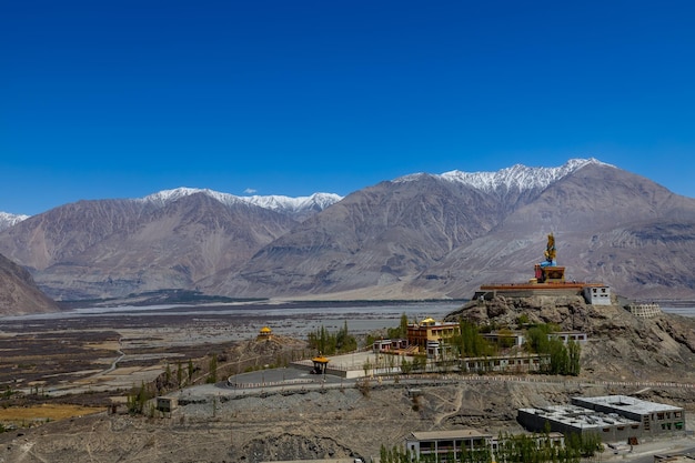 Große sitzende Buddha-Statue im Diskit-Kloster mit Himalaya-Gebirge im Hintergrund, Ladakh, Indien