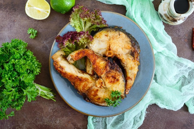 Große Steaks von gegrilltem Fisch mit Salat auf einem Teller Die Draufsicht