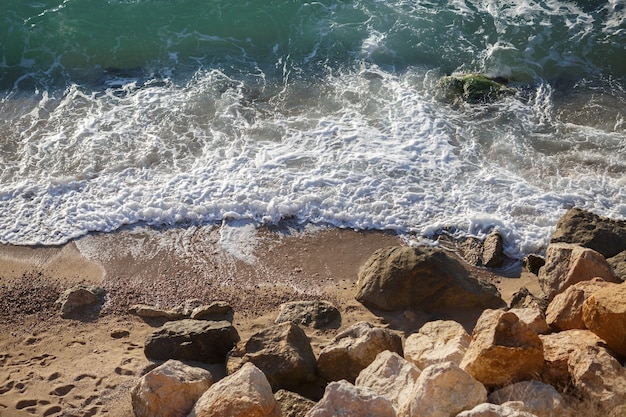 Große Steine am Sandstrand und Wellen, die ihn waschen. Malerischer Blick auf die Küstenlandschaft