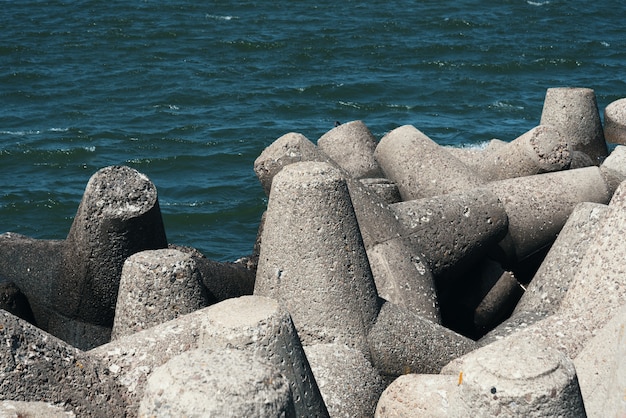 Große Steine liegen am Strand vor den Wellen.