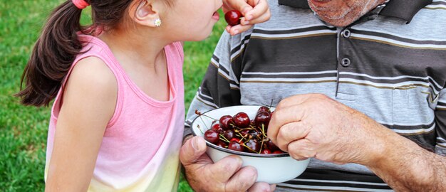 Großeltern füttern das Kind mit Kirschen.selektiver Fokus.Natur