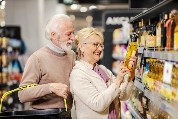 Foto großeltern kaufen olivenöl im supermarkt und schauen sich den preis an