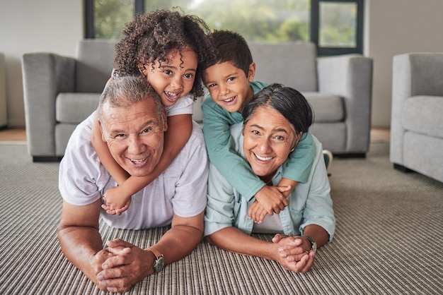 Großeltern Kinder oder Bindung in lustigem Spiel auf dem Boden des Wohnzimmers des Hauses oder der Familie Porträtlächeln oder glücklicher älterer Mann und reife Frau, die Enkelkinder oder Kinder zusammen in der Lounge babysitten