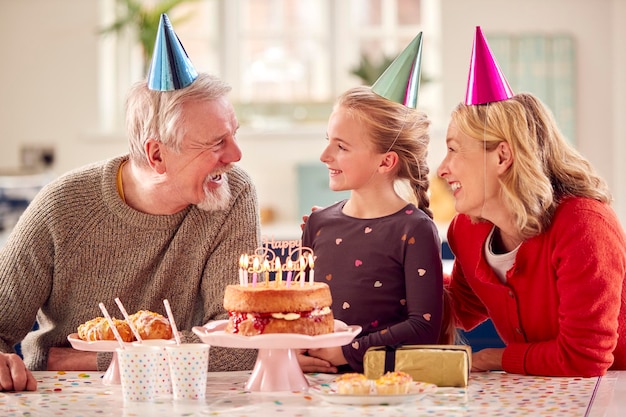 Großeltern mit Enkelin feiern gemeinsam Geburtstag mit Party zu Hause