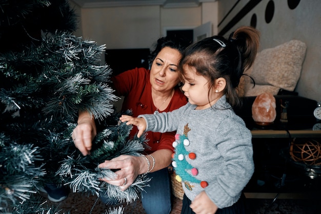 Großeltern schmücken den Weihnachtsbaum mit ihrer kleinen Enkelin