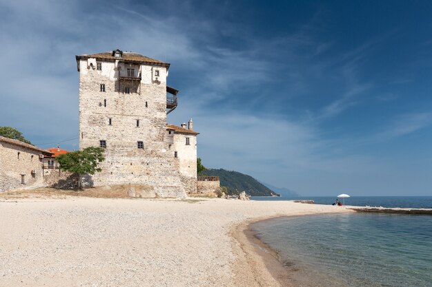 Großer alter byzantinischer Turm an einem leeren Strand einer kleinen griechischen Mittelmeerstadt gegen