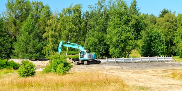 Großer Bagger auf dem Feld vor dem Wald