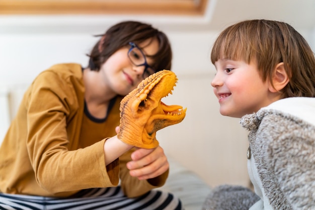 Großer Bruder, der zu Hause mit einem Kleinkind spielt, mit einem Dinosaurier, der ein interessantes Spiel entwickelt Gute Beziehungen zwischen Familienmitgliedern Konzept