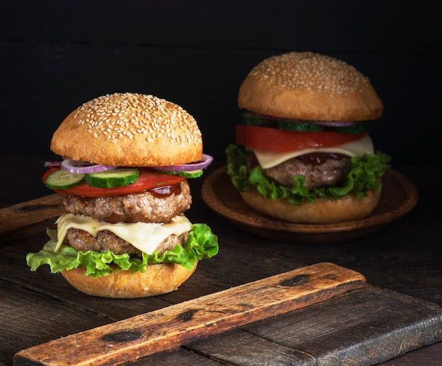 Großer Burger mit zwei gebratenen Koteletts, Käse und Gemüse