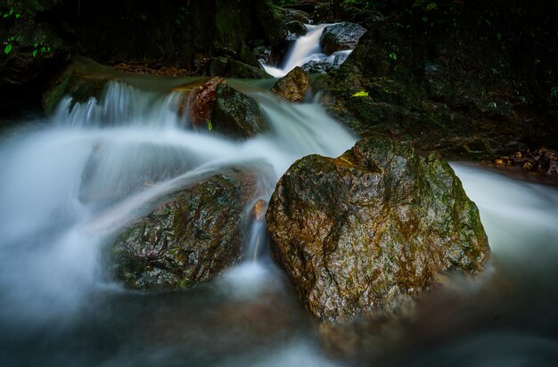 Großer Felsen im Wald am Nangrong-Wasserfall, Provinz Nakhon Nayok, Thailand mit langer Belichtung morgens.