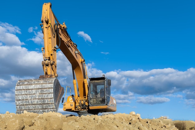 großer gelber bagger, der auf der baustelle arbeitet und die erde bewegt