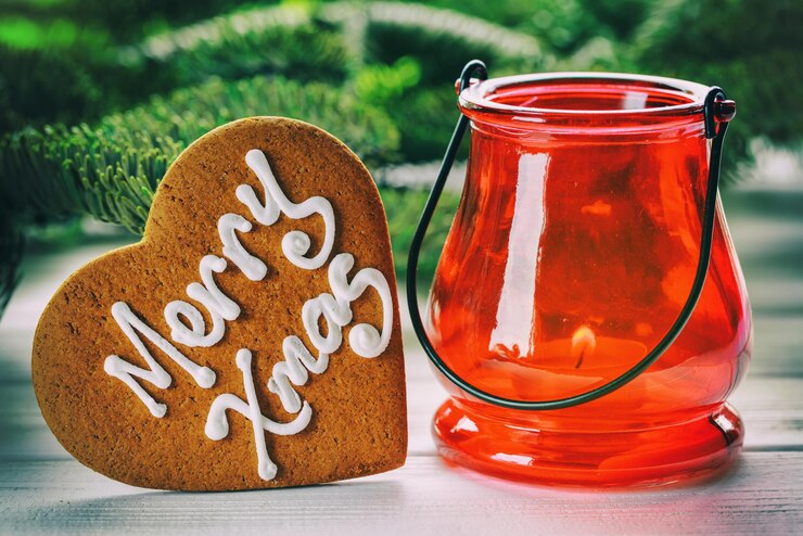 Foto großer herzförmiger keks mit handschrift "glückliches weihnachten" und roter kerzenhalter weihnachtskonzept