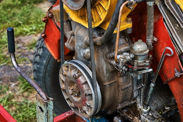 Großer leuchtend roter hausgemachter Krafttraktor mit unverschlossenen Rohren und Drähten in der Nähe