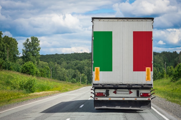 Großer lkw mit der nationalflagge von italien, die auf der autobahn bewegt