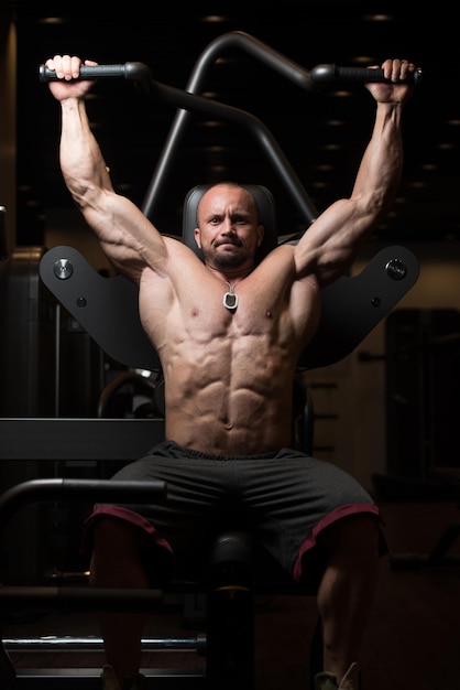 Großer Mann in der Turnhalle und trainieren wieder auf Maschine muskulöser athletischer Bodybuilder Modellübung im Fitness-Center