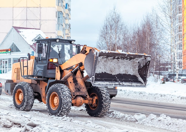 Großer orangefarbener Traktor reinigt Schnee von der Straße Reinigung und Reinigung von Straßen in der Stadt