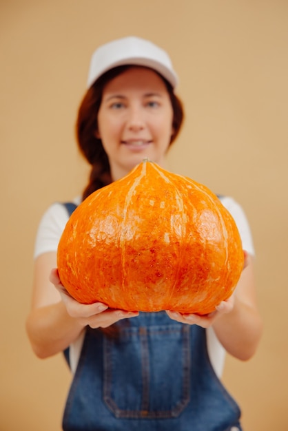 Großer oranger reifer Kürbis für den Halloween-Urlaub wird von einem verschwommenen Bio-Lebensmittel einer Bäuerin gehalten