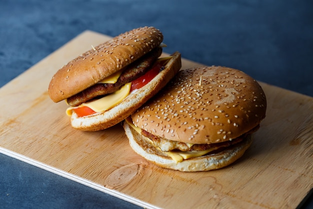 Großer saftiger Burger mit Schnitzelkäse und Tomaten. Fastfood.