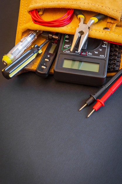 Großer Satz Werkzeuge in Wildledertasche auf Schwarzraum, die vom Elektromeister vor der Reparatur oder dem Bau vorbereitet wurden