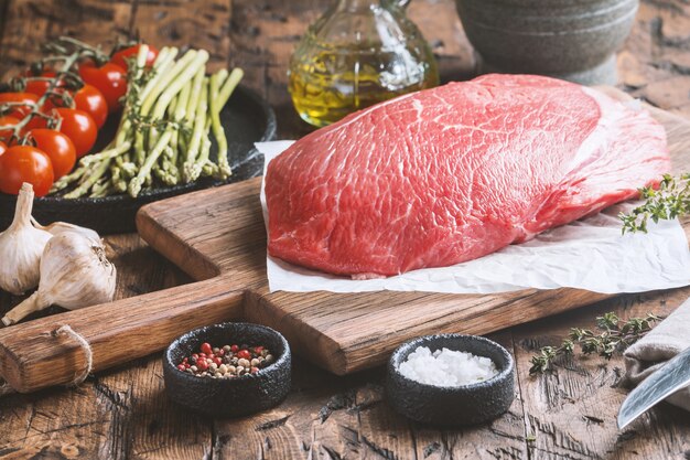 Großer Schnitt von rohem Rindfleisch mit Thymian Knoblauch und Gewürzen auf Holz