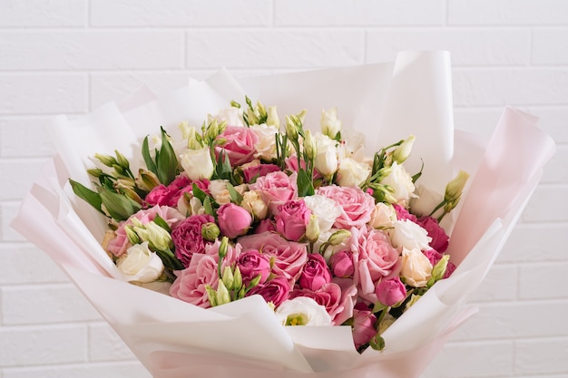 Großer Strauß schöner und leuchtend weißrosa Rosen und Eustoma in rosa Verpackung