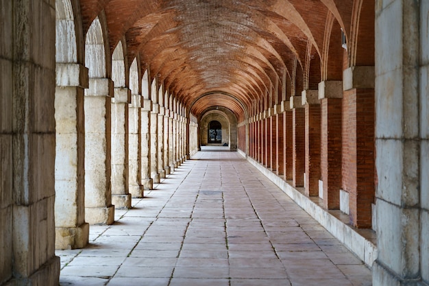 Großer symmetrischer Außenkorridor mit Bögen und Säulen im alten Königspalast von Aranjuez