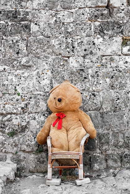 Großer Teddybär sitzt auf einem Stuhl vor dem Gebäude