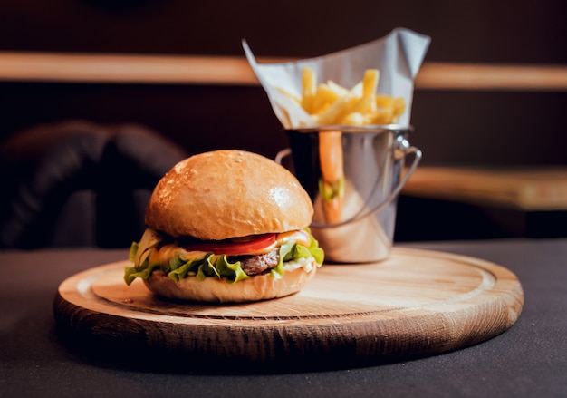 Großer und leckerer Burger mit Feuer auf dem Holzschreibtisch