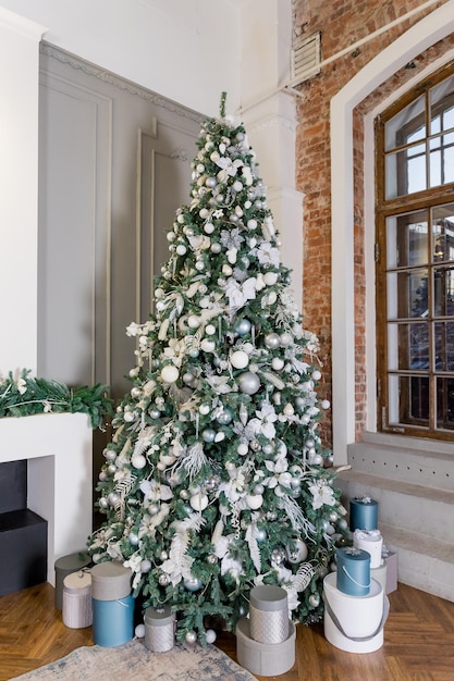 Großer Weihnachtsbaum mit silberweißen blauen Kugeln Neujahrs- und Weihnachtsattribut für Grußkarten oder Glückwünsche märchenhafte AtmosphäreUrlaub Viele Geschenkboxen unter dem Baum