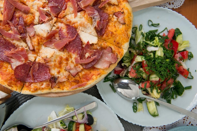 Foto großes abendessen mit pizza, salat und bratkartoffeln. geburtstag, weihnachten, neujahr, festliches abendessen, ein tisch-, versammlungs- oder feierkonzept.