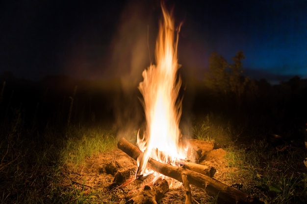 Großes Feuer im orangefarbenen Lagerfeuer bei Sonnenuntergang mit blauem dunklem Nachthimmel