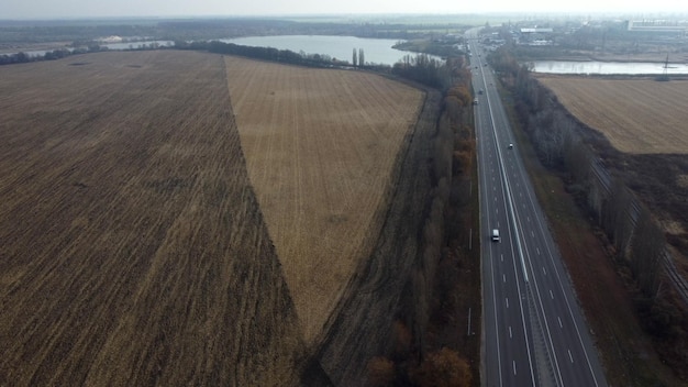 Großes gepflügtes Feld mit gepflügtem Land und gelbem trockenem Stroh nach der Ernte von Weizen ein See ein Autobahnwitz