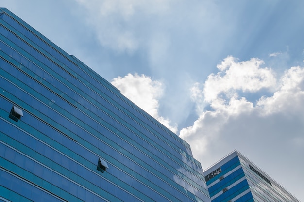 Großes Glasbürogebäude mit blauem Himmel und weißer Wolke