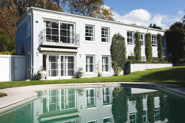 Großes Haus mit Swimmingpool und Bäumen im sonnigen Garten. Luxuriöser Lebensstil im Ruhestand, Zeit zu Hause verbringen.